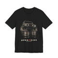 Black tee, front print: 4x4 wading dark water at night, headlights on (angled three-quarter view) with NO ROAD REQUIRED lettering under GRENADIER wordmark, Black