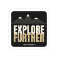 Explore Further die-cut sticker: mountain peaks above big EXPLORE FURTHER lettering in cream and tan on a black badge