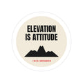 Elevation Is Attitude die-cut sticker: ELEVATION IS ATTITUDE lettering over a black mountain on a round cream badge